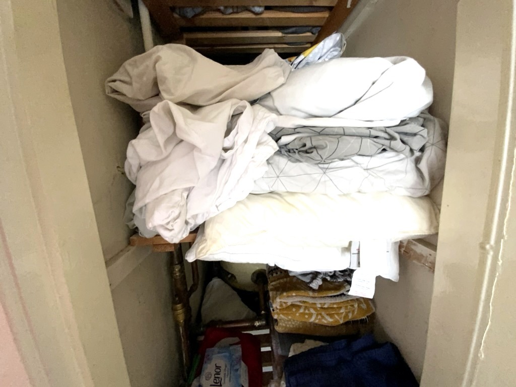 Airing cupboard with the hot water cylinder hidden behind stored bedding, a common access problem under the new EPC evidence standards